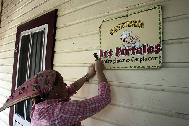 La propietaria de la cafetería Los Portales coloca un cartel para identificar su establecimiento en Jesús Menéndez, un municipio del oriente cubano. La tributación de los negocios privados engrosará desde ahora las arcas municipales, para mejorar las condiciones de cada localidad.