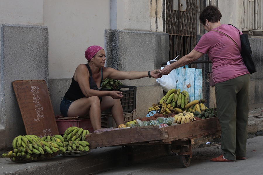 Una vendedora ambulante ofrece productos del agro a una clienta